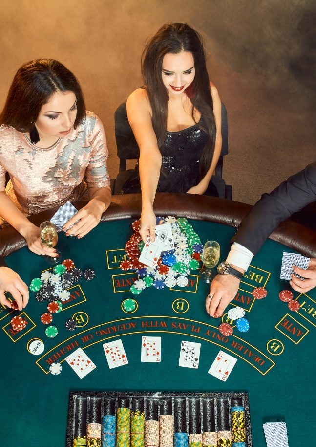 Poker players sitting around a table at a casino.