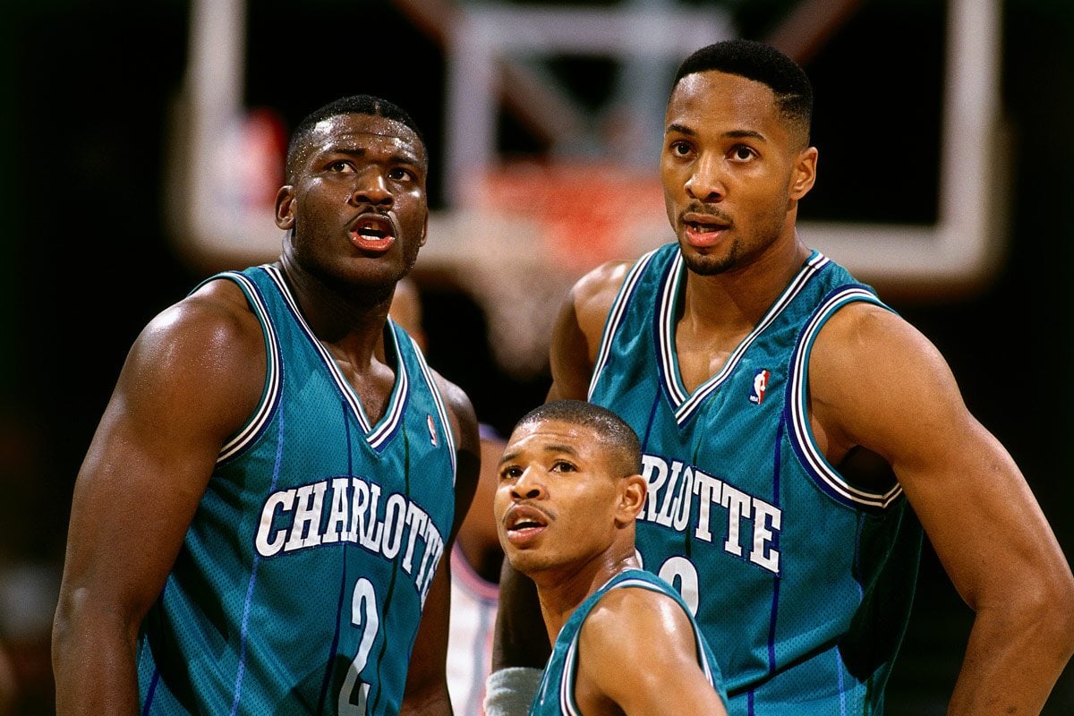 Muggsy Bogues standing between two taller players