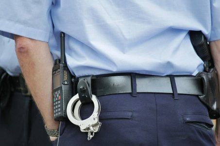 Polizist in Uniform mit Handschellen, Funkgerät und Pistole