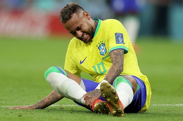 Soccer star Neymar holds his ankle following an injury during a game