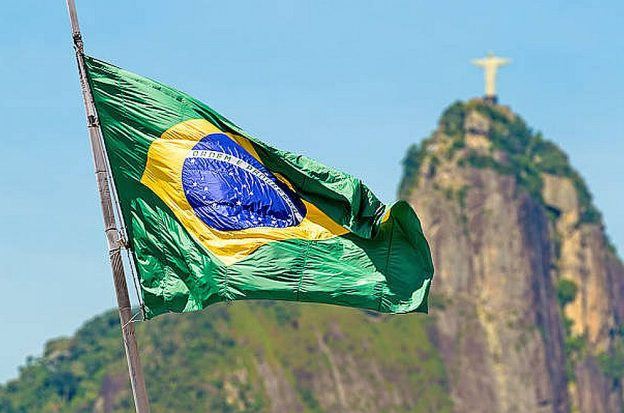 The Brazilian flag flying against a background of the Christ the Redeemer statue